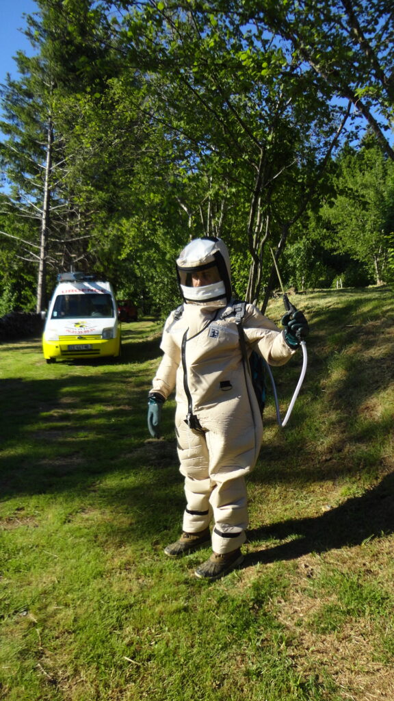 urgence guêpes et frelons - gérant en tenu de protection contre les guêpes devant son véhicule de fonction
