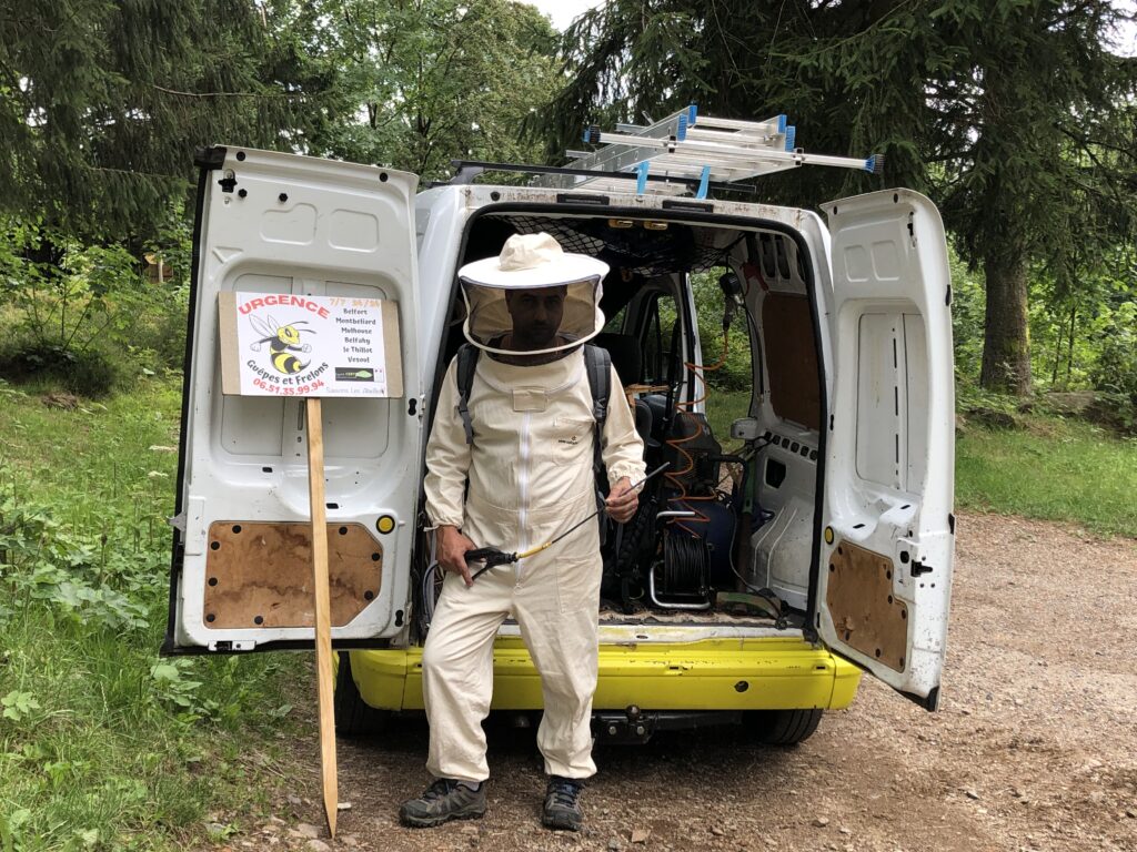 urgence guêpes et frelons - gérant en tenu de protection contre les guêpes devant son véhicule de fonction